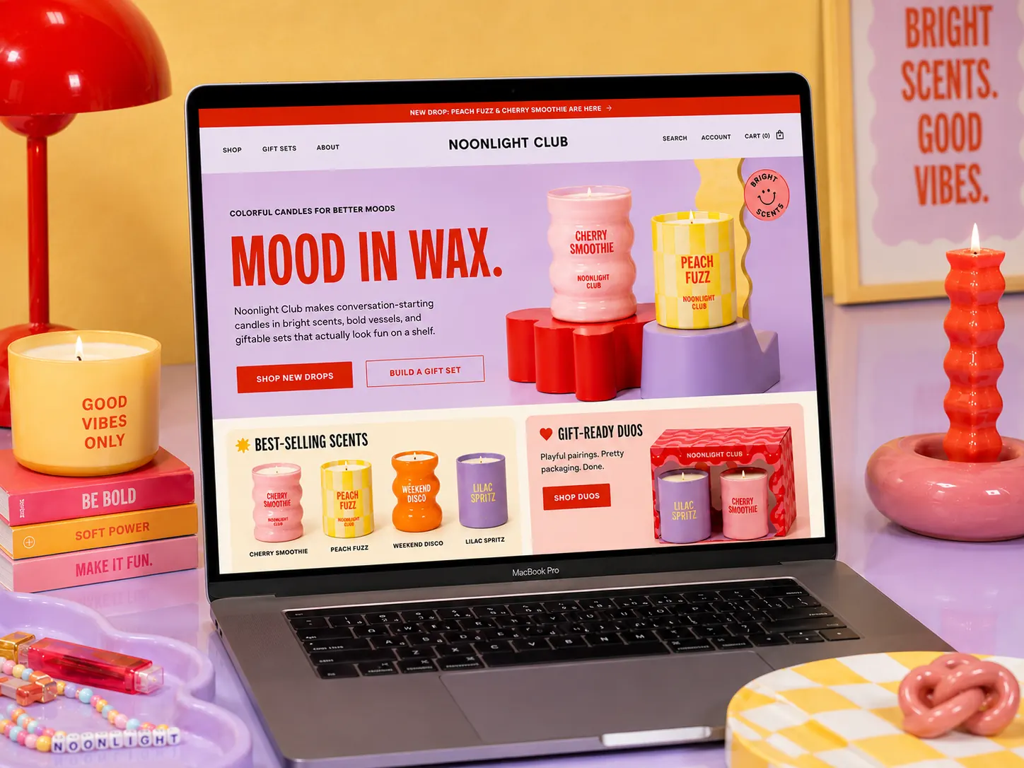 Noonlight Club e-commerce homepage shown on a laptop inside a bright product set